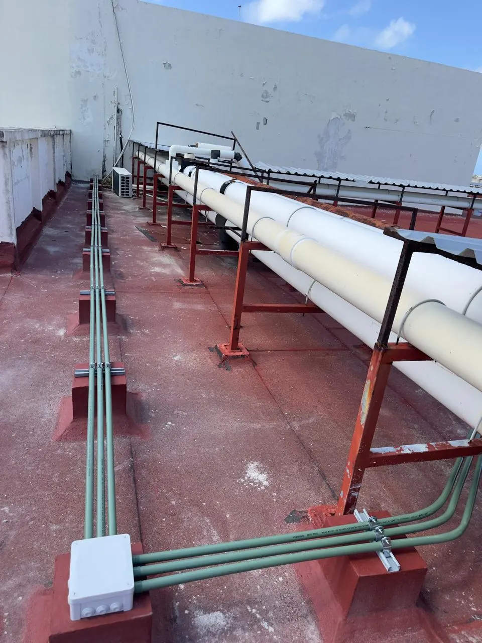 Tres tuberías conduit sobre bases en azotea, con caja de registro